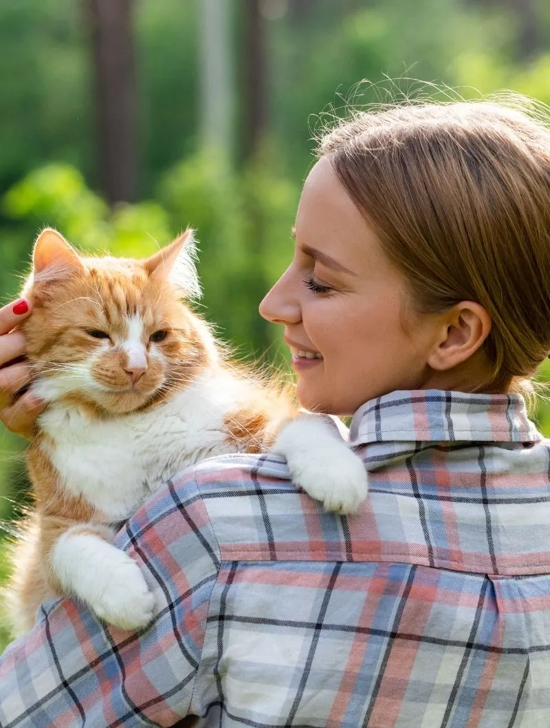 orange-cat A woman embraces a cat in her arms
